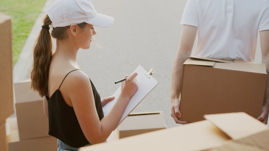 A woman with long brown hair tied in a ponytail, wearing a white cap and a black sleeveless top, is standing outside in natural daylight, holding a clipboard and writing with a marker. She is engaged 